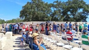 People line up against the limestone Flood Memorial Wall in prayer.