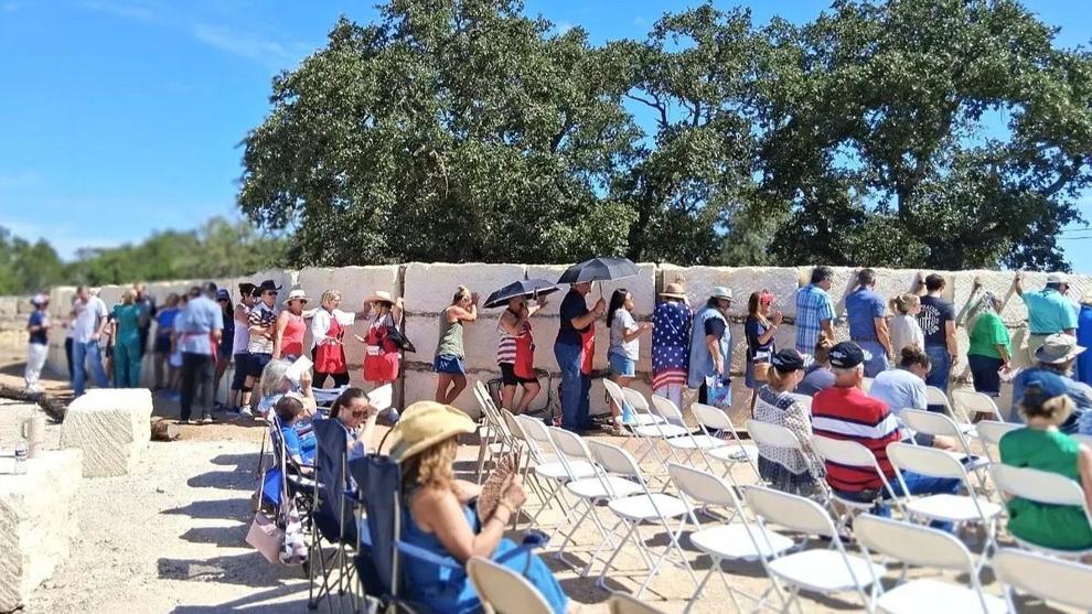 People line up against the limestone Flood Memorial Wall in prayer.